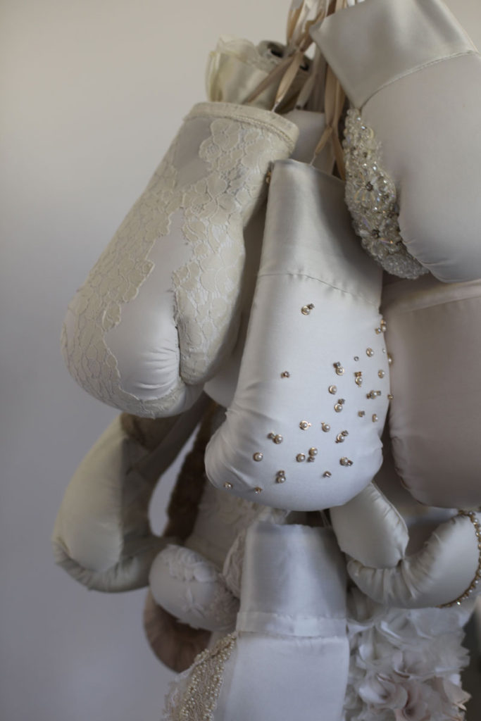 Detail of large sculpture featuring boxing gloves and wedding dresses